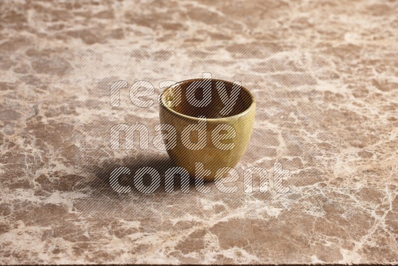 A multicolored pottery cup on beige marble background