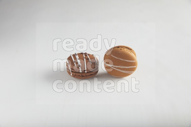 45º Shot of of two assorted Brown Irish Cream, and Brown white Chocolate Caramel macarons on white background