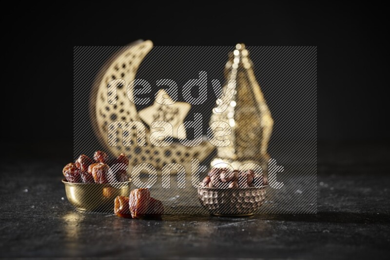 Dates in a metal bowl with hazelnuts beside golden lanterns in a dark setup