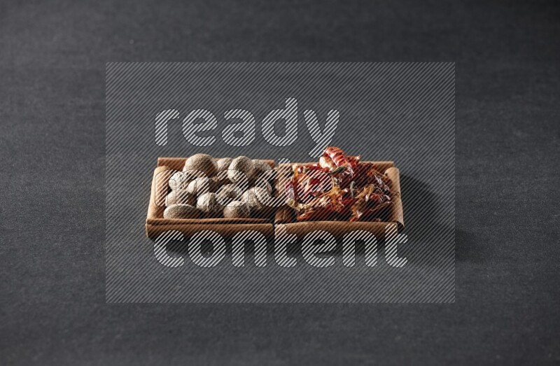 2 squares of cinnamon sticks full of nutmegs and dried red chilis on black flooring