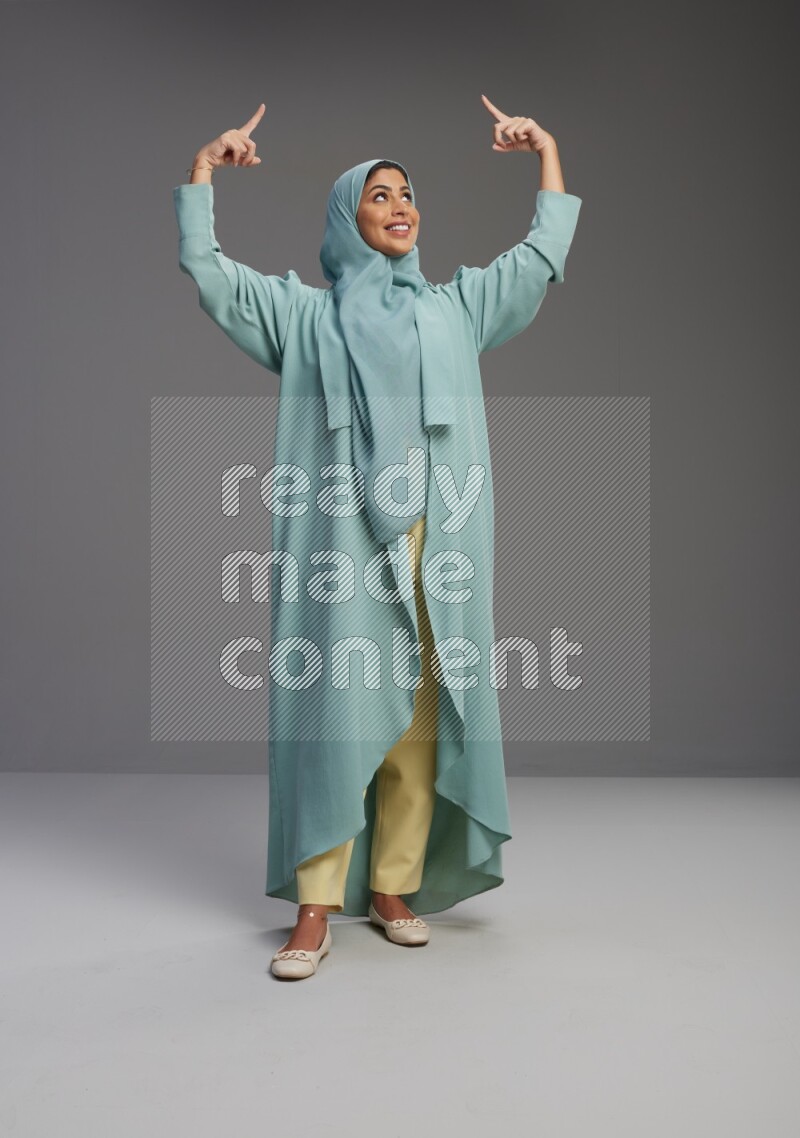 Saudi Woman wearing Abaya standing interacting with the camera on Gray background