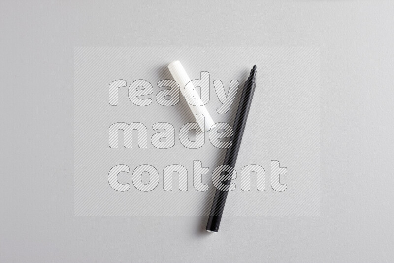 A close-up showing an open single coloring pen with a cap on grey background