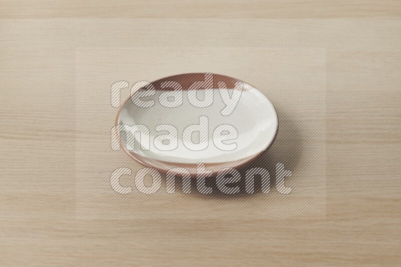 A multicolored pottery plate on light wooden background
