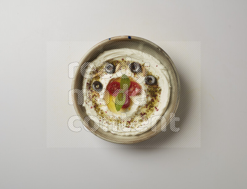 Lebnah garnished with cherry tomato, mint, olives & pine nuts in a grey pottery plate on a white background