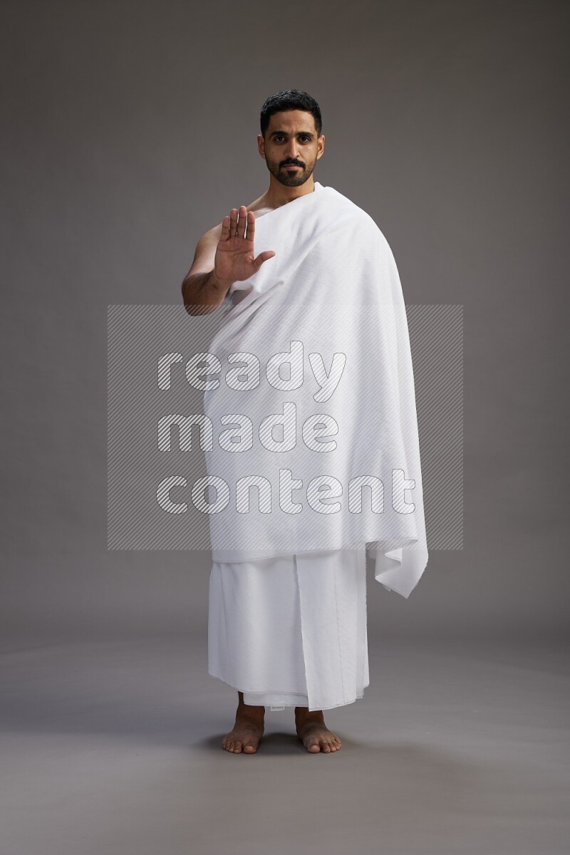 A man wearing Ehram Standing Interacting with the camera on gray background
