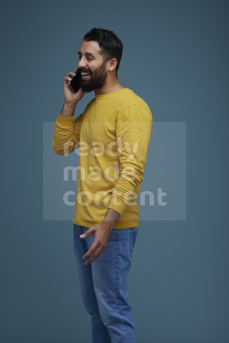 A man having a calling in a blue background wearing a yellow shirt