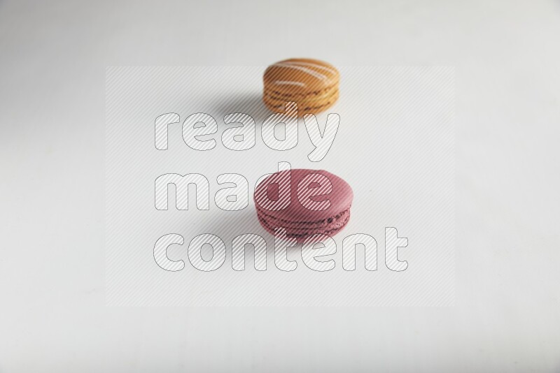 45º Shot of of two assorted Brown Irish Cream, and Red Cherry macarons on white background