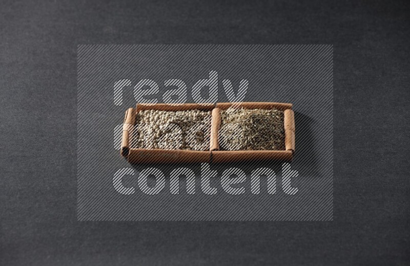 2 squares of cinnamon sticks full of white peppers and cumin on black flooring