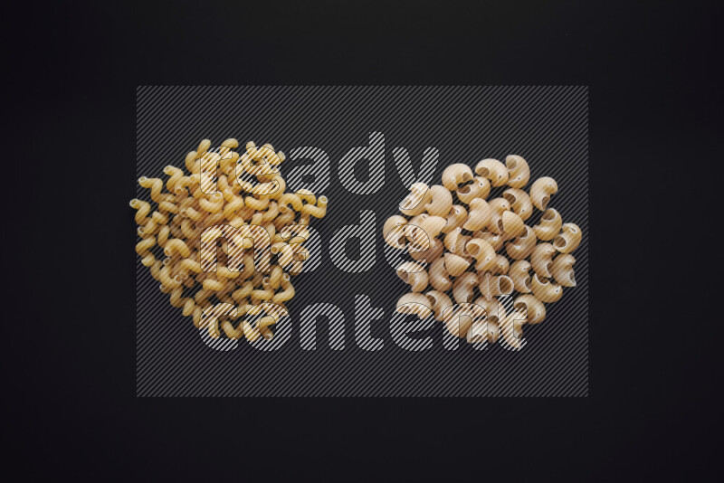 Different pasta types in bunches on black background