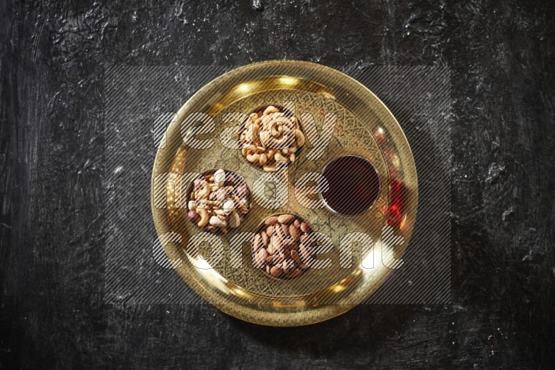 Nuts in metal bowls with Hibiscus on a tray in dark setup