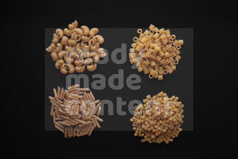 Different pasta types in bunches on black background