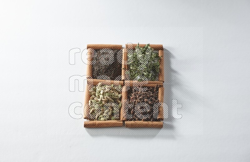 4 squares of cinnamon sticks full of tea, cardamom, mint and cloves on white flooring