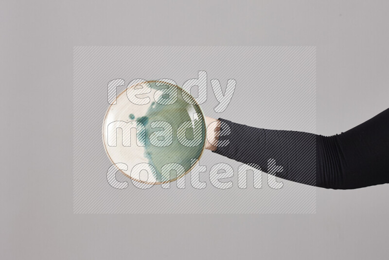 A woman in black abaya holding different pottery essentials in different positions