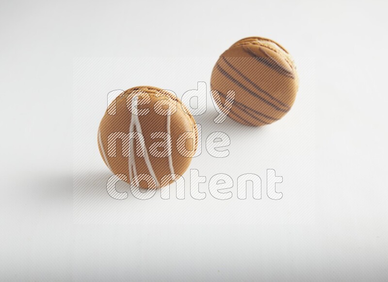 45º Shot of of two assorted Brown Irish Cream, and light brown  Almond Cream macarons on white background