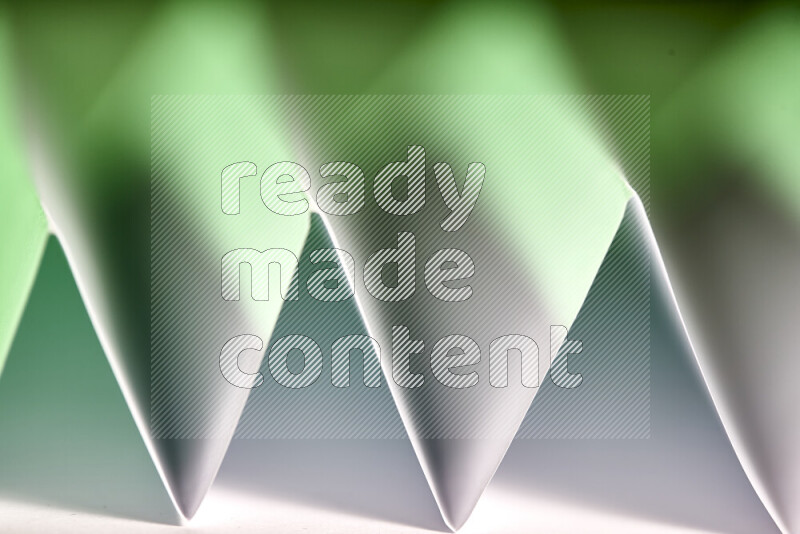 A close-up abstract image showing sharp geometric paper folds in white and green gradients