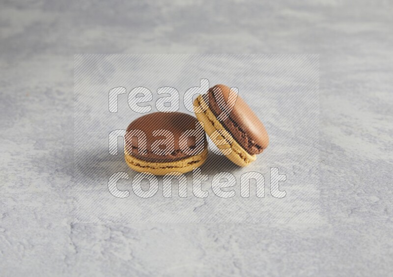 45º Shot of two Yellow and Brown Chai Latte macarons r on white  marble background