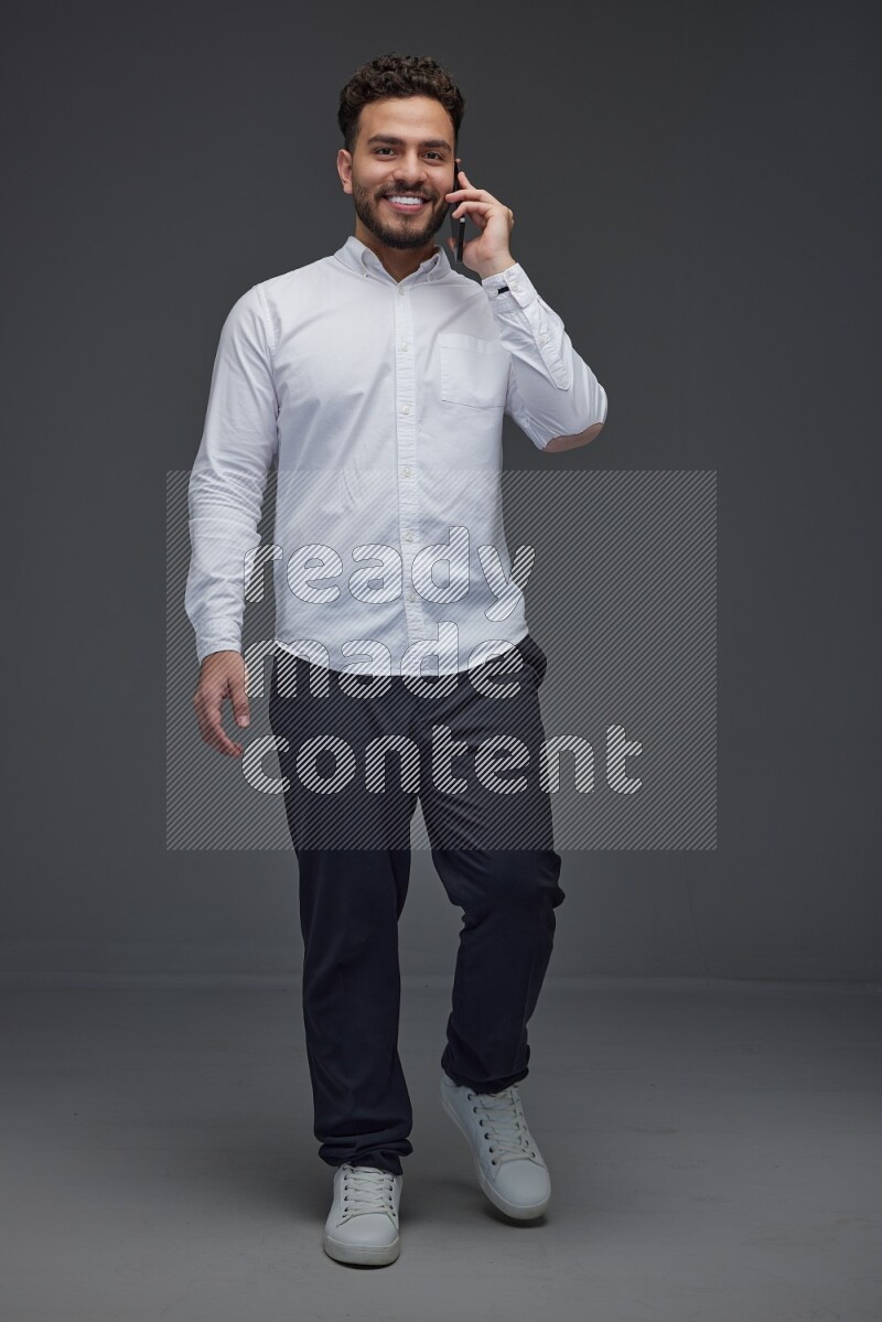 A man wearing smart casual talking in the phone eye level on a gray background