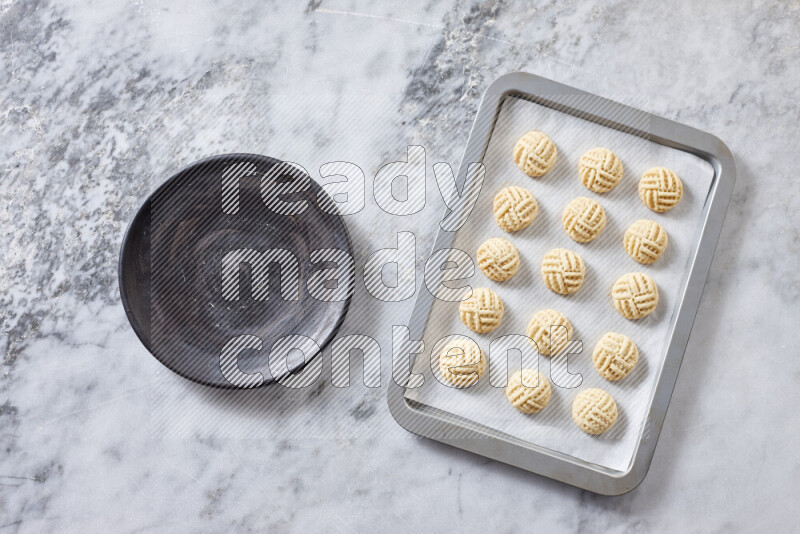 كحك خطوة بخطوة بمكوناته سمن، سكر، دقيق، سمسم، خميرة، ماء ونكهة الكحك على خلفية رخام رمادي