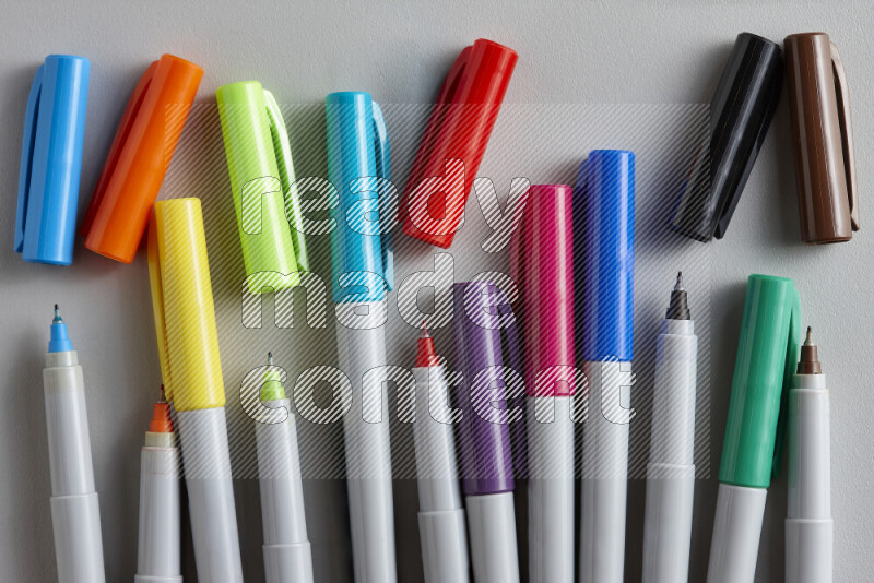 An arrangement of coloring pens in different colors on grey background