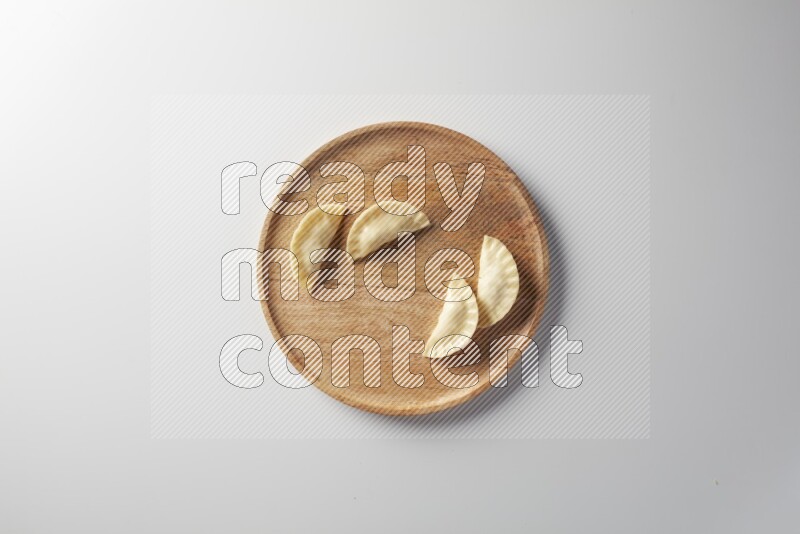 Four Sambosas on a wooden round plate on a white background