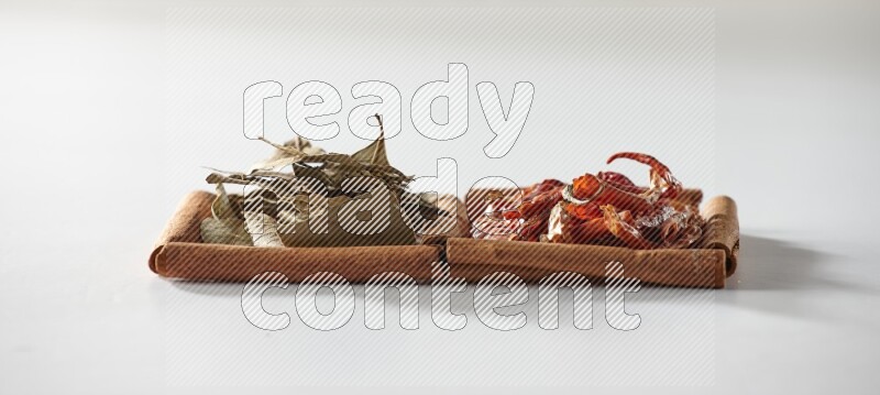 2 squares of cinnamon sticks full of dried red chilis and bay laurel leaves on white flooring