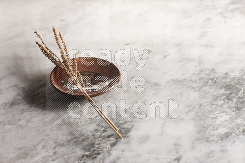 Wheat stalks on decorative pottery plate on grey marble background