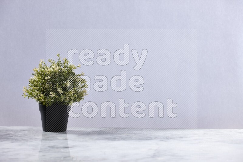 Artificial plant in black pot on grey marble background