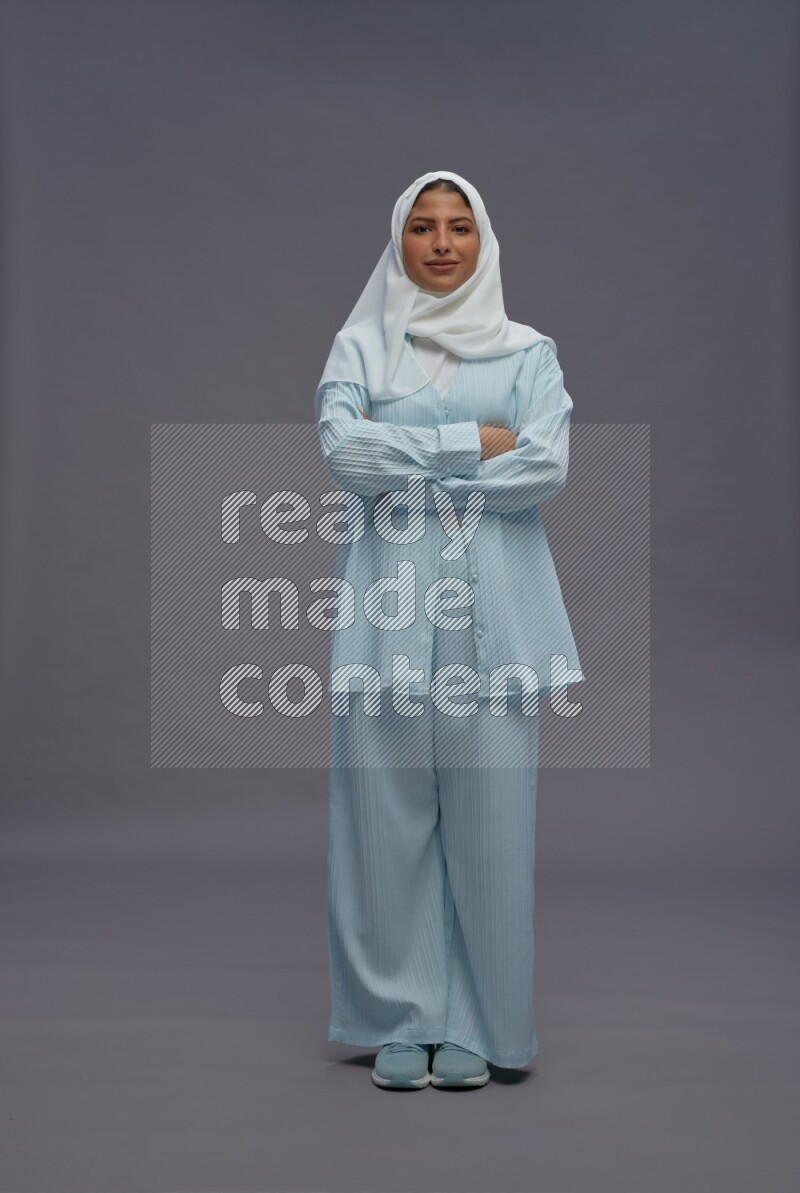 Saudi woman wearing hijab clothes standing with crossed arms on gray background