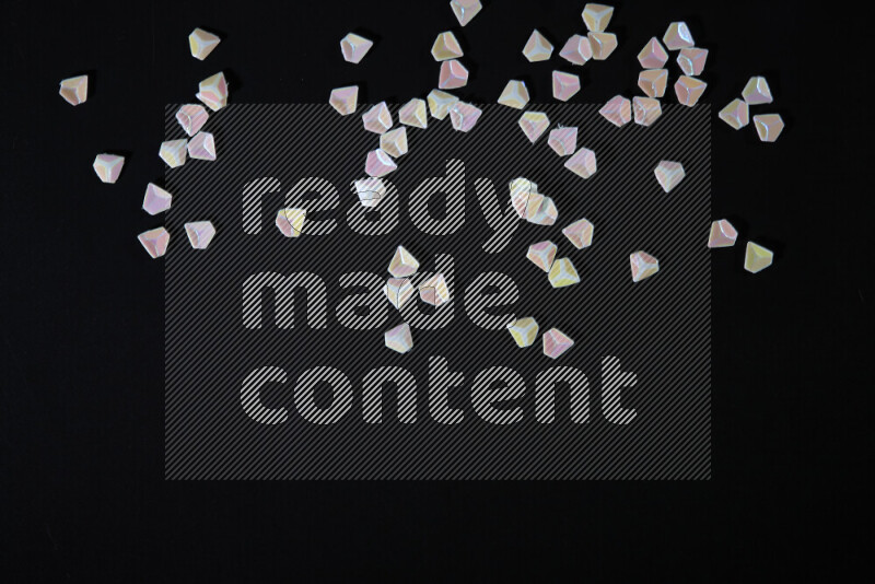 Colorful plastic shards for decoration scattered on a black background