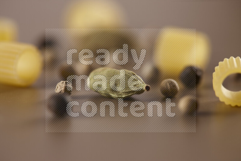 معكرونة مع مكونات متنوعة من الطماطم والثوم والبصل والفلفل الأحمر والفلفل الأسود والفلفل الأبيض وأوراق الغار وإكليل الجبل والهيل على خلفية بيج