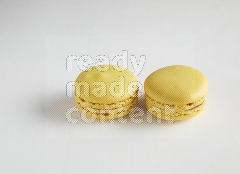 45º Shot of two Yellow Lemon macarons on white background