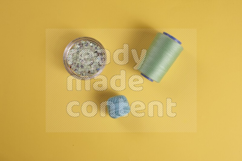 A green collection of sewing and tailoring tools arranged on a yellow background