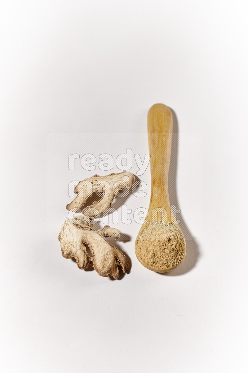 A wooden spoon full of ground ginger powder on white background
