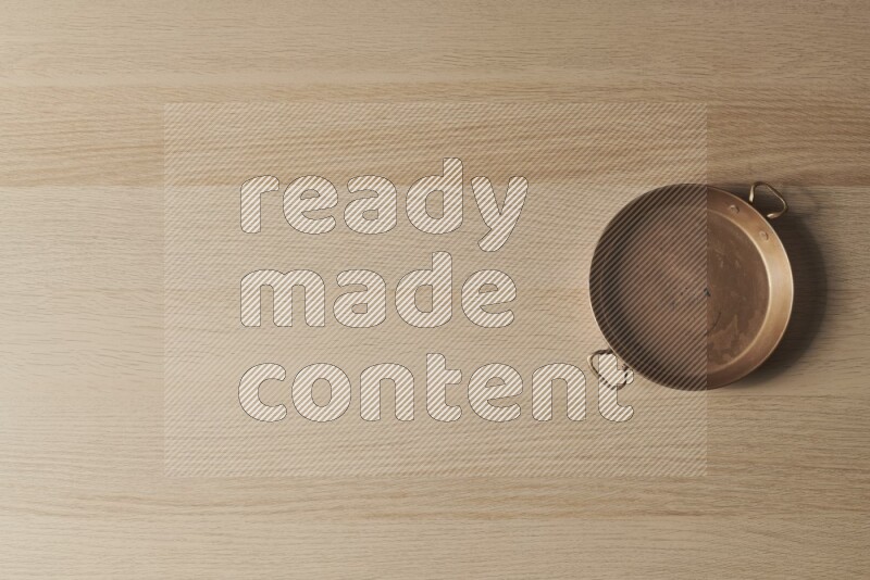 A small copper pan on light wooden background