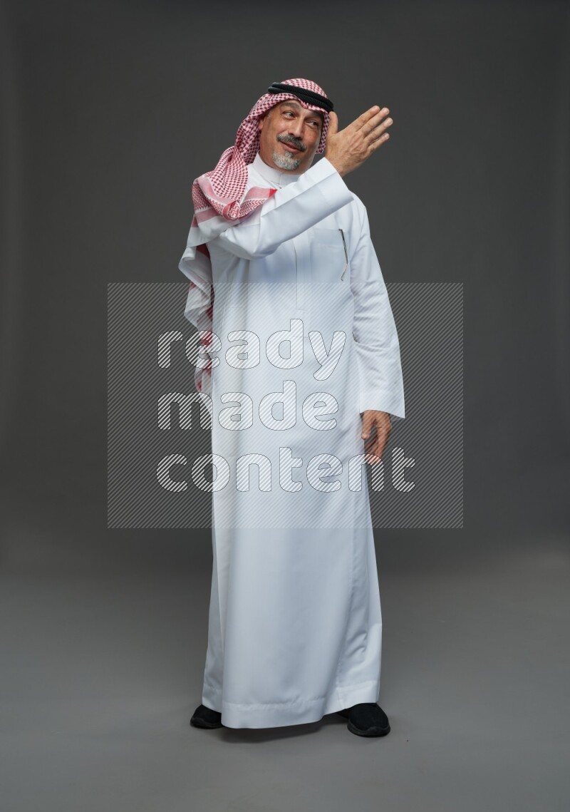 Saudi man with shomag Standing Interacting with the camera on gray background