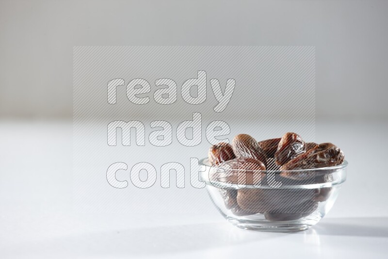 A glass bowl full of dried dates on a white background in different angles