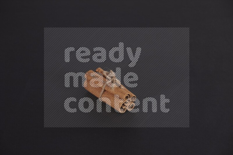 4 أعواد من القرفة مربوطة علي خلفية سوداء