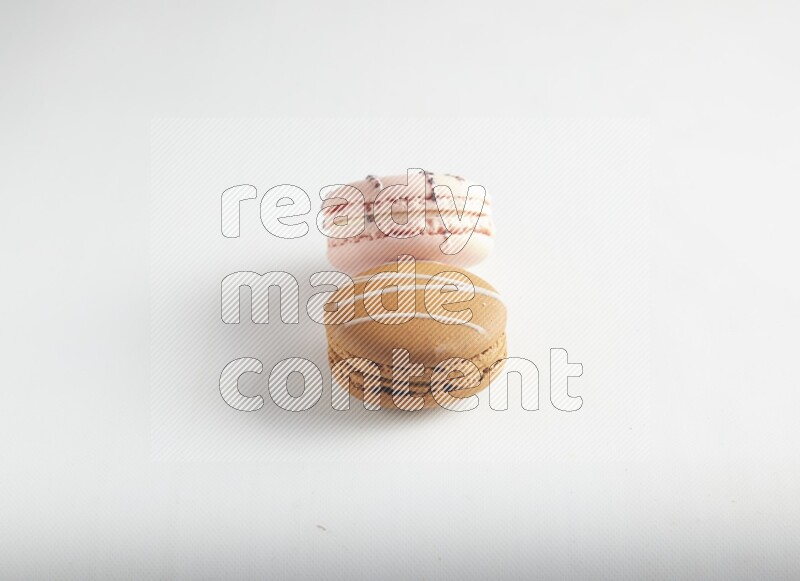 45º Shot of of two assorted Brown Irish Cream, and pink orange blossom macarons on white background