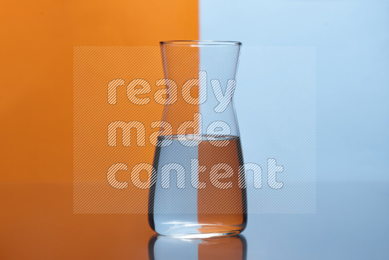 The image features a clear glassware filled with water, set against orange and light blue background