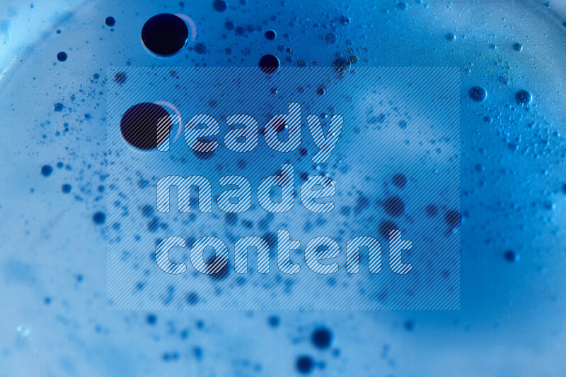 لقطات مقربة لقطرات ألوان مائية زرقاء على سطح الزيت على خلفية زرقاء