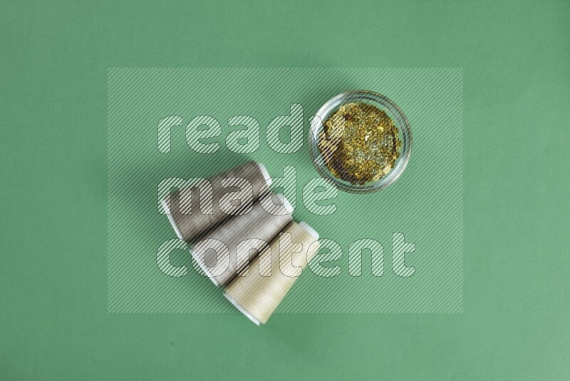 A brown collection of sewing and tailoring tools arranged on a green background