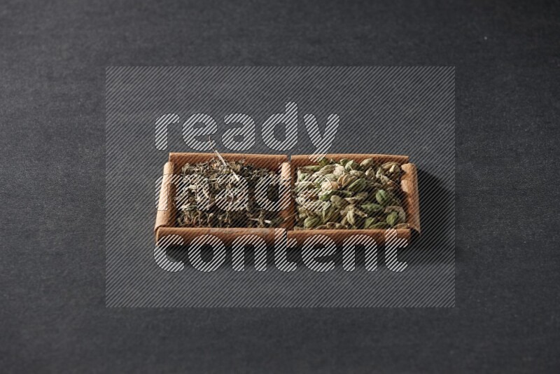 2 squares of cinnamon sticks full of cardamom and dried basil on black flooring