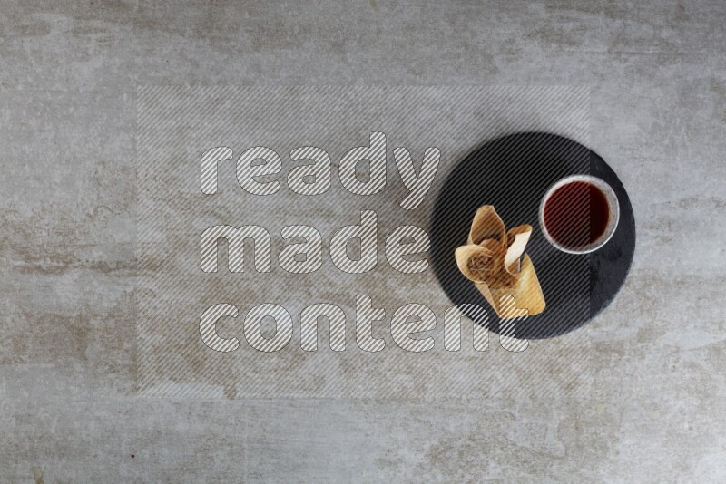 wonton cups with soy sauce ramkin on circle slate on grey textured counter top