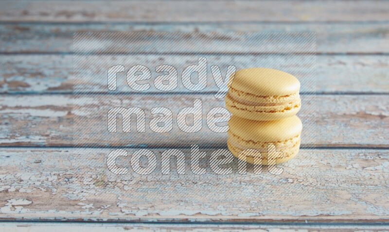 45º Shot of two Yellow Vanilla macarons on a light blue wooden background