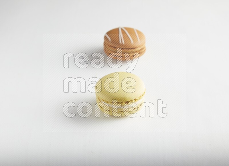 45º Shot of of two assorted Brown Irish Cream, and Yellow Lime macarons on white background