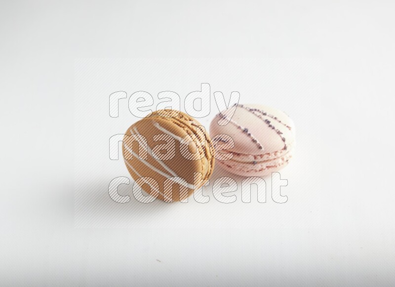 45º Shot of of two assorted Brown Irish Cream, and pink orange blossom macarons on white background