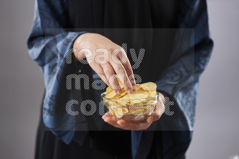Woman in abaya holding different kinds of snacks in different positions