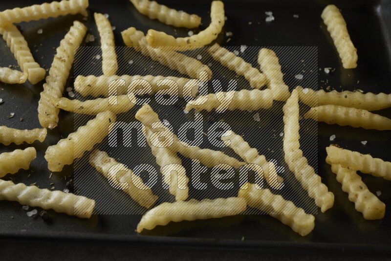 crinkle fries in a black stainless steel rectangle tray on grey textured counter top