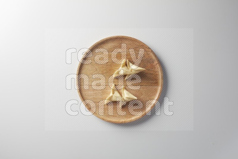 Four Sambosas on a wooden round plate on a white background