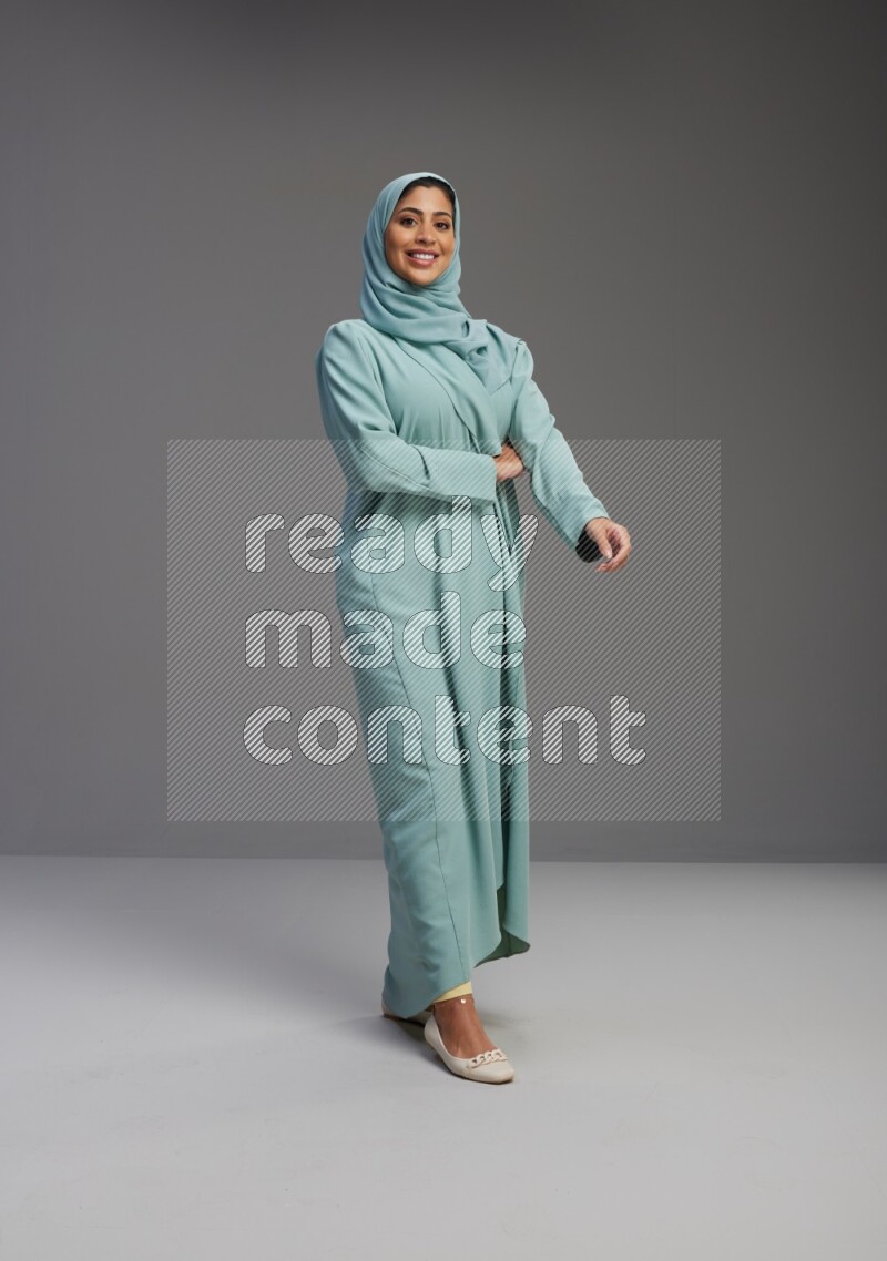 Saudi Woman wearing Abaya standing interacting with the camera on Gray background